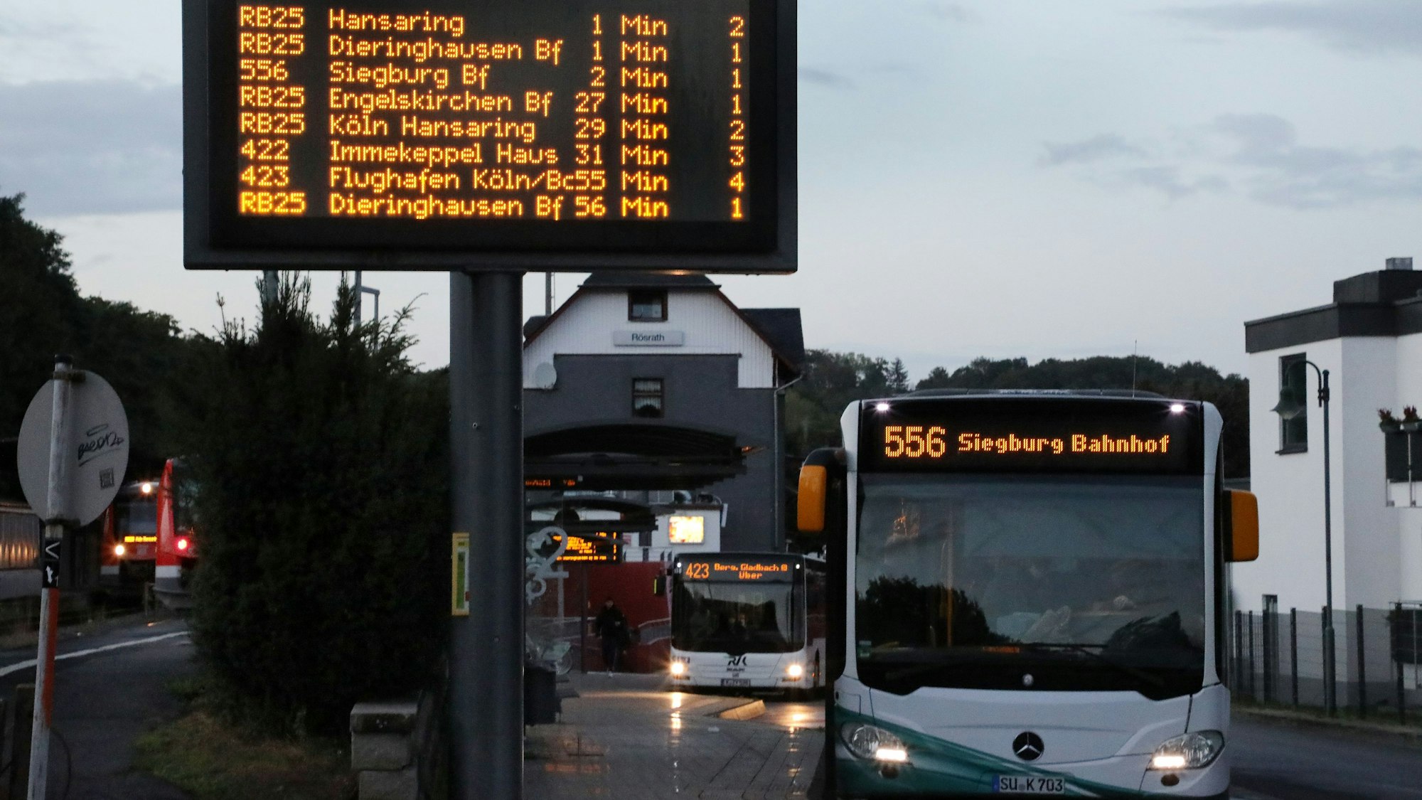 Ein Bus, daneben eine große digitale Anzeigetafel mit Busverbindungen.