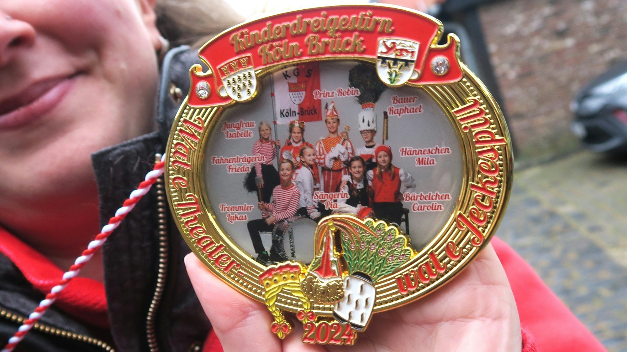 Acht Kinder im Kostüm sind auf dem Orden zu sehen.