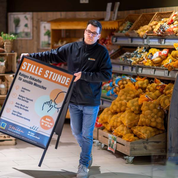Dirk Steilen trägt in seinem Edeka-Markt einen Aufsteller, der auf die Stille Stunde hinweist, in der auf grelles Licht und Werbung verzichtet wird.