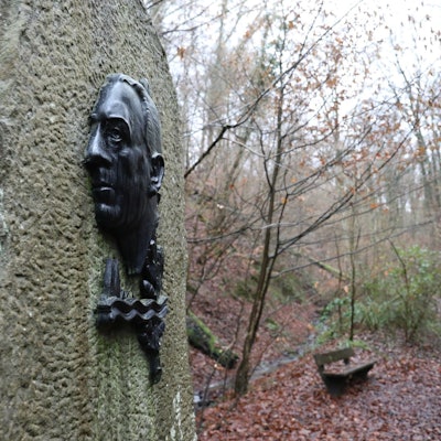 An einem großen Stein ist Bronzerelief mit einem Porträt von Willi Ostermann angebracht.