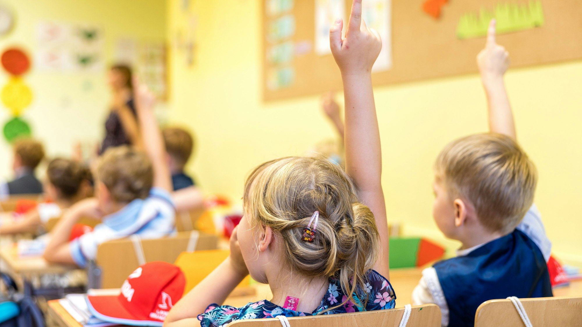 Eine erste Klasse mit Kindern, die aufzeigen.