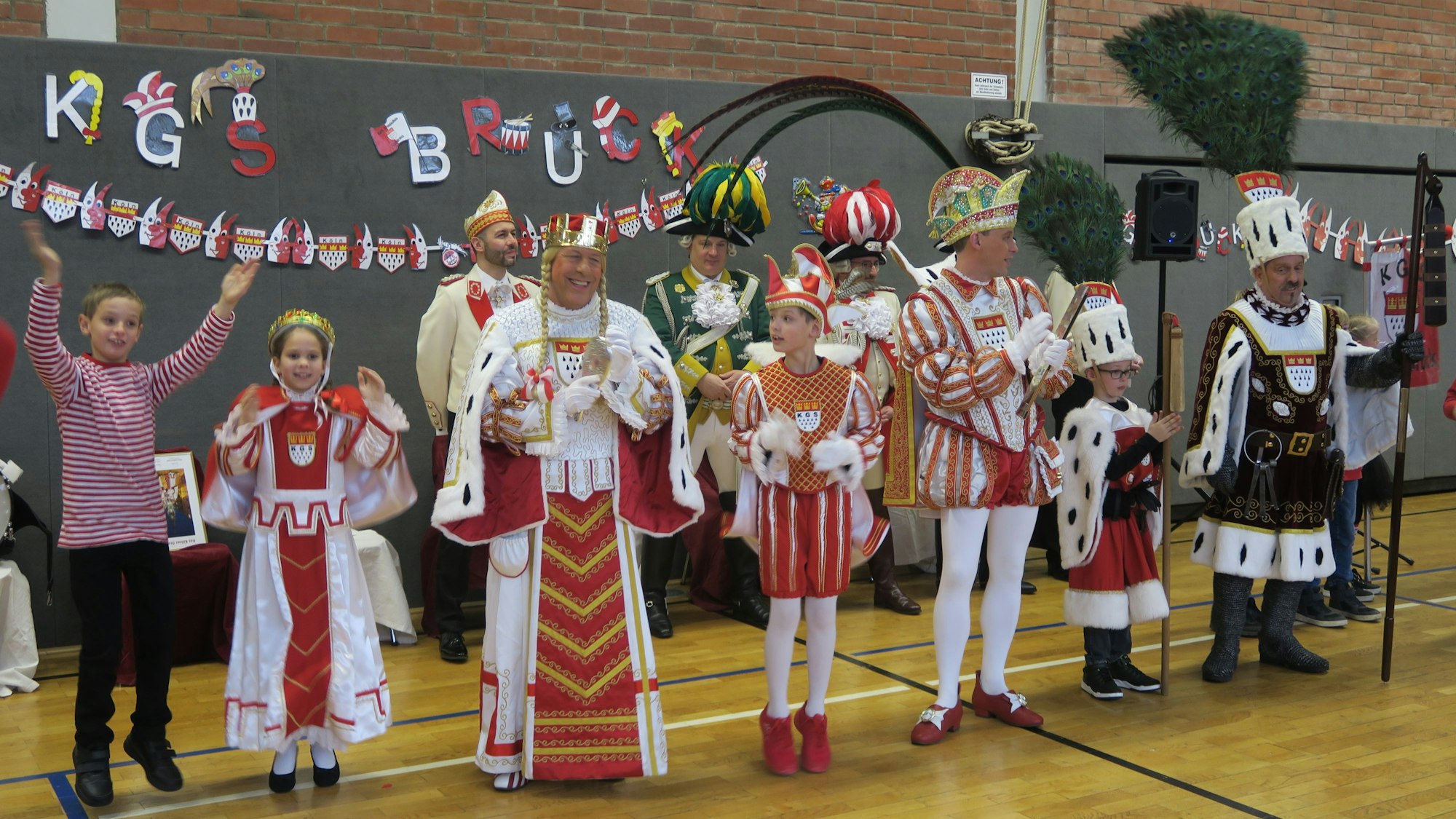 Dreigestirn in Groß und Klein stehen in einer Turnhalle.