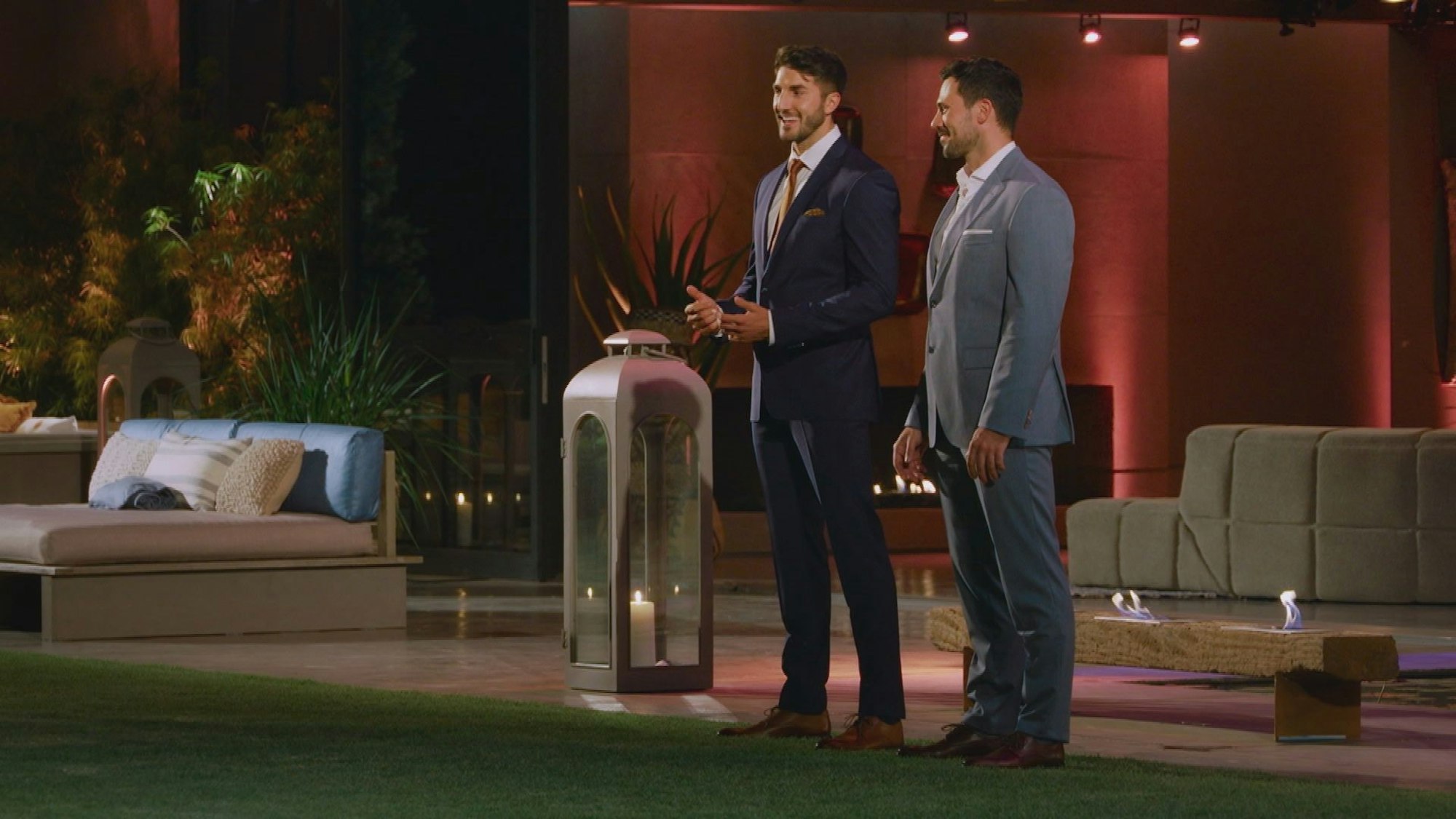 Zwei Männer in Anzügen stehen auf einer Terrasse.