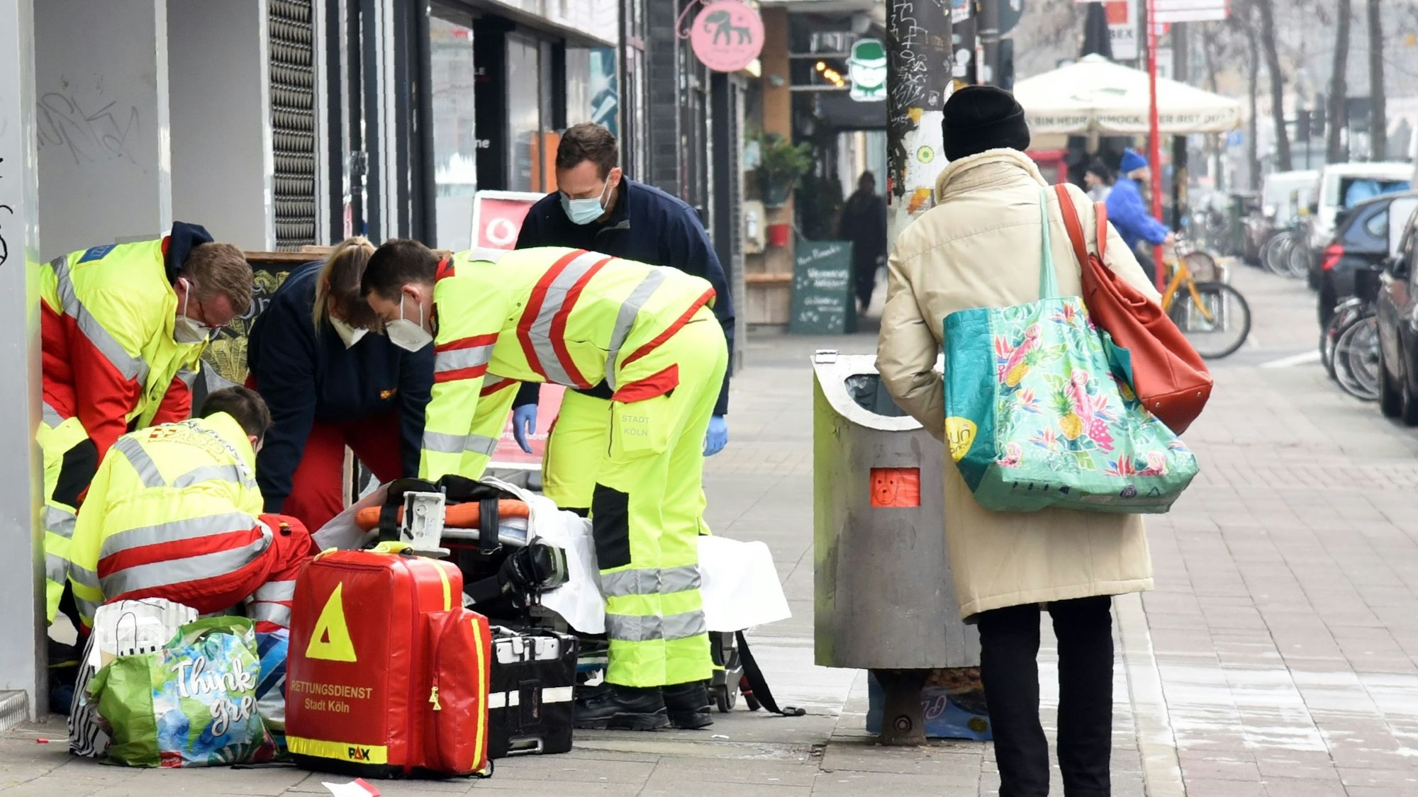 Rettungssanitäter und Notarzt kümmern sich um einen Obdachlosen auf der Aachener Straße in Köln.