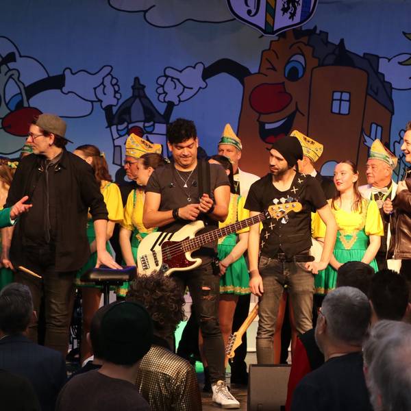 Musiker stehen bei einer Karnevalssitzung auf der Bühne.