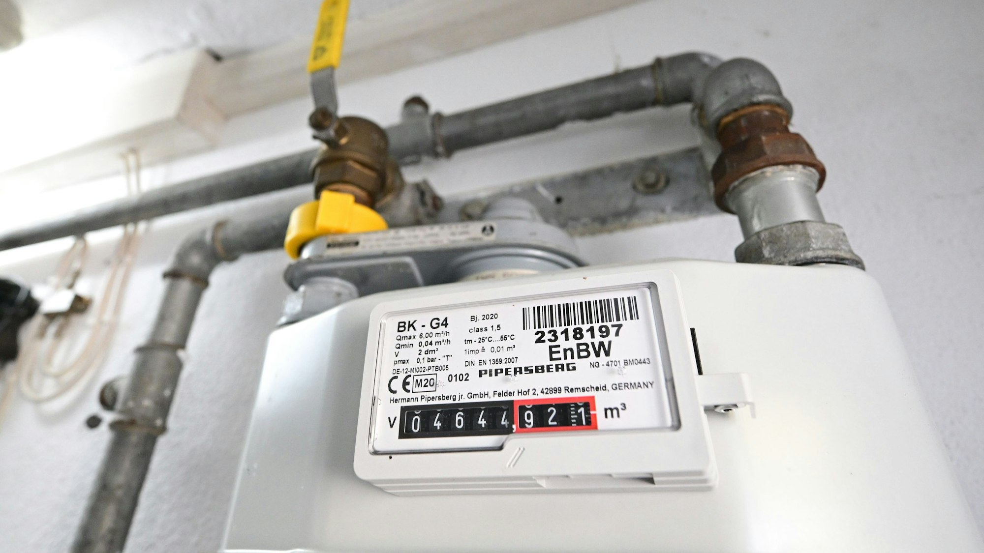 Ein Gaszähler hängt in einem Privathaus an einer weißen Wand.