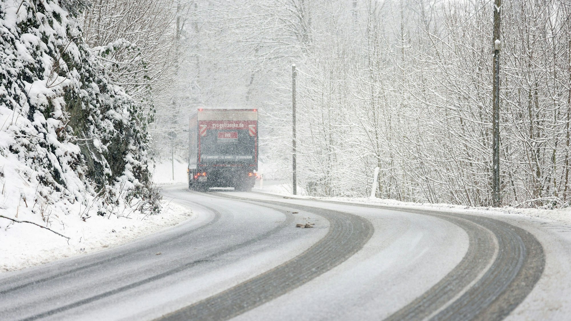Winter im Siegerland. Winterliche Straßenverhältnisse. Ein Lastwagen fährt über die verschneite L907 bei Siegen-Gosenbach.