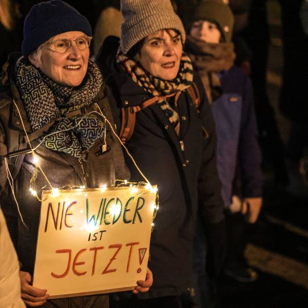Eine Frau trägt ein Schild mit der Aufschrift ·„Nie wieder ist jetzt“ auf der Demo des Bündnisses gegen „Rassismus in Köln“.