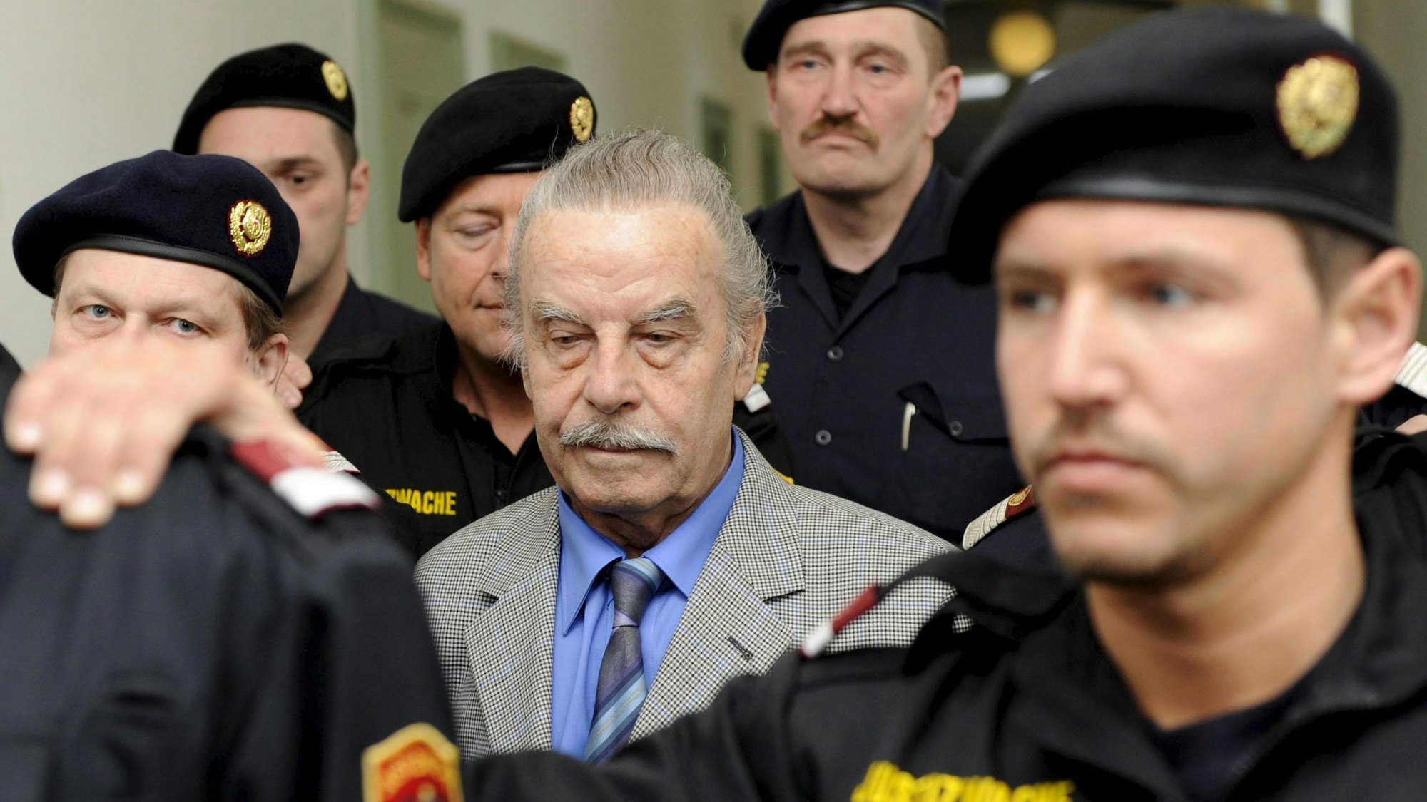 Josef Fritzl wird von mehreren Polizistin begleitet.