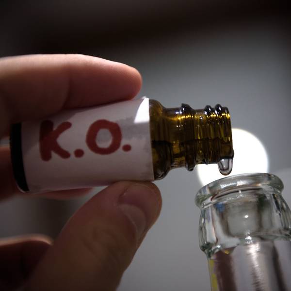 Aus einem Fläschchen mit der Aufschrift „K.O.“ wird eine klare Flüssigkeit in eine Glasflasche geträufelt.