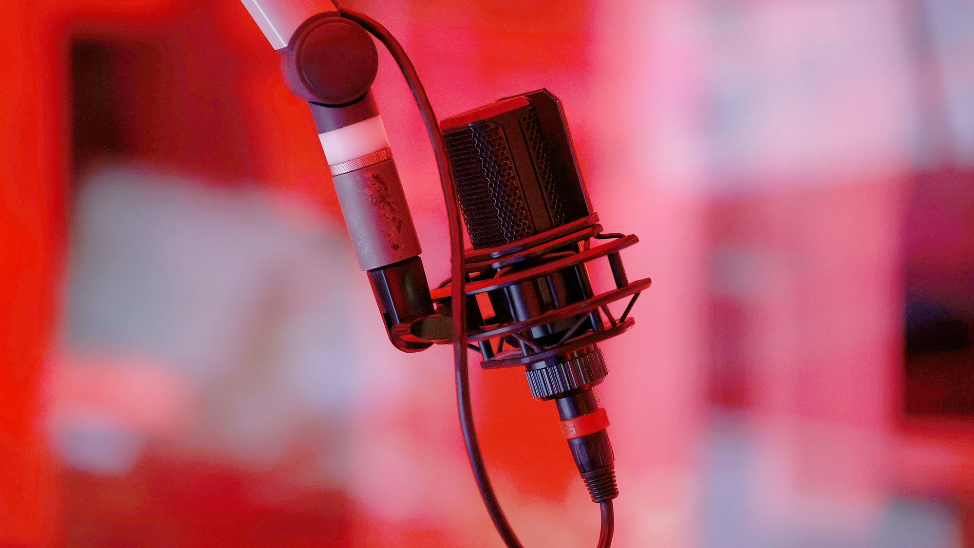 Ein Mikrofon in einem rot beleuchteten Tonstudio