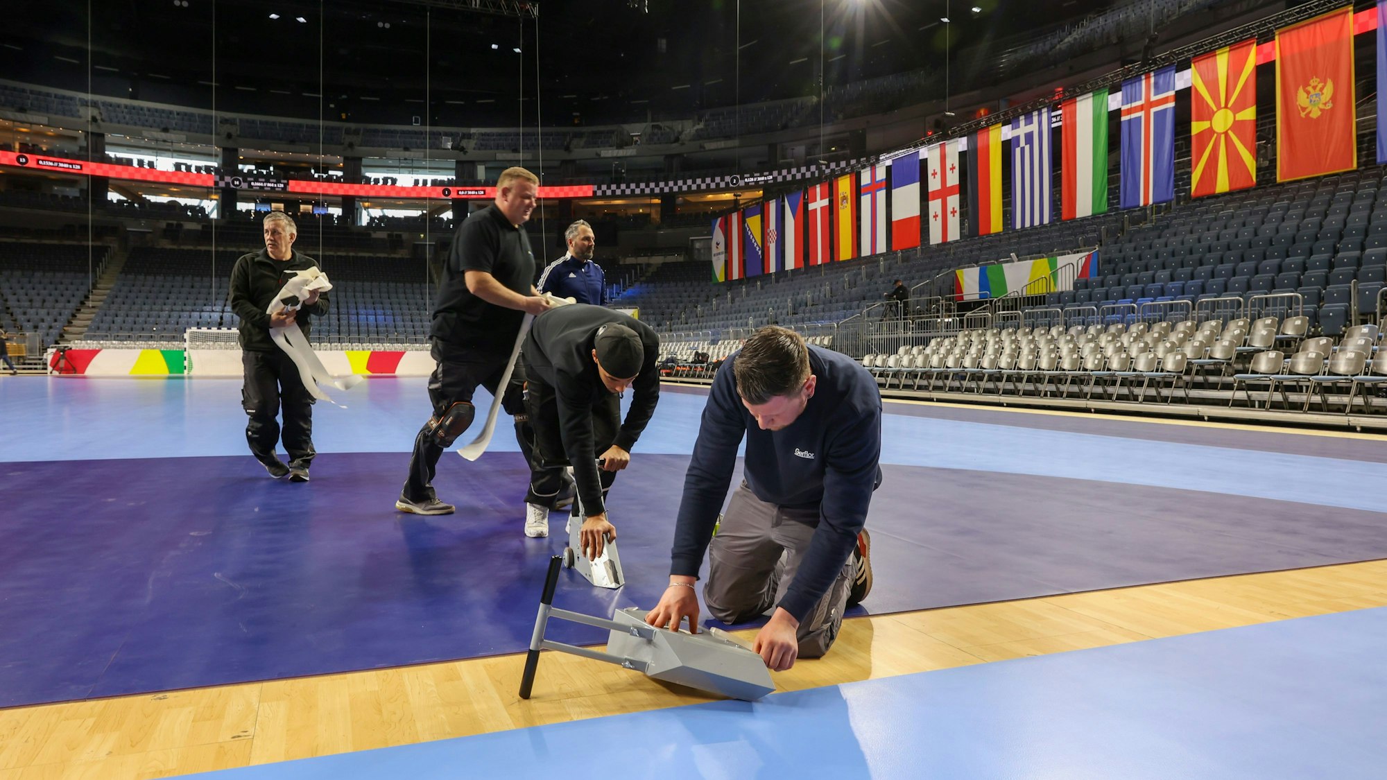 In der Lanxess-Arena wird die Spielmatte für die Handball-Europameisterschaft verklebt.