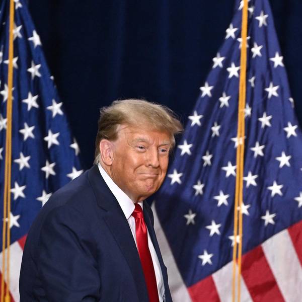 Ex-US-Präsident Donald Trump steht auf einer Bühne vor zwei Flaggen der Vereinigten Staaten und blickt lächelnd ins Publikum.