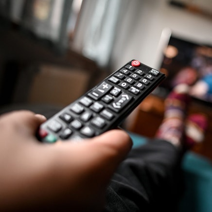 Eine Fernbedienung zeigt in Richtung eines Fernsehers.