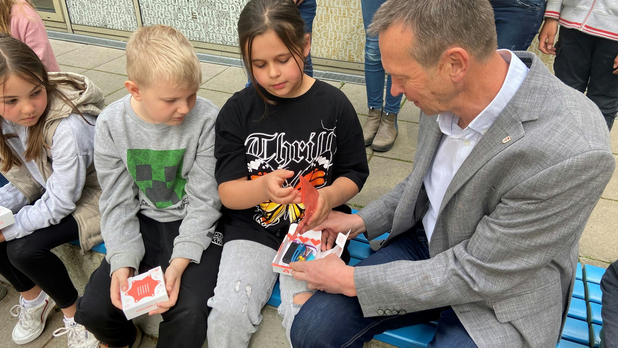 Auf einer Bank sitzen Kinder neben einem Mann.