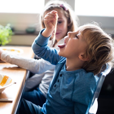 Ein Junge steckt trockene Spaghetti in den Mund.