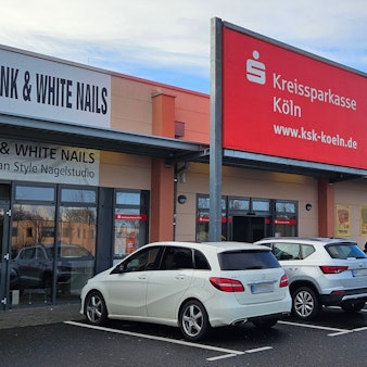 Vor einer Niederlassung der Kreissparkasse Köln parken Autos.