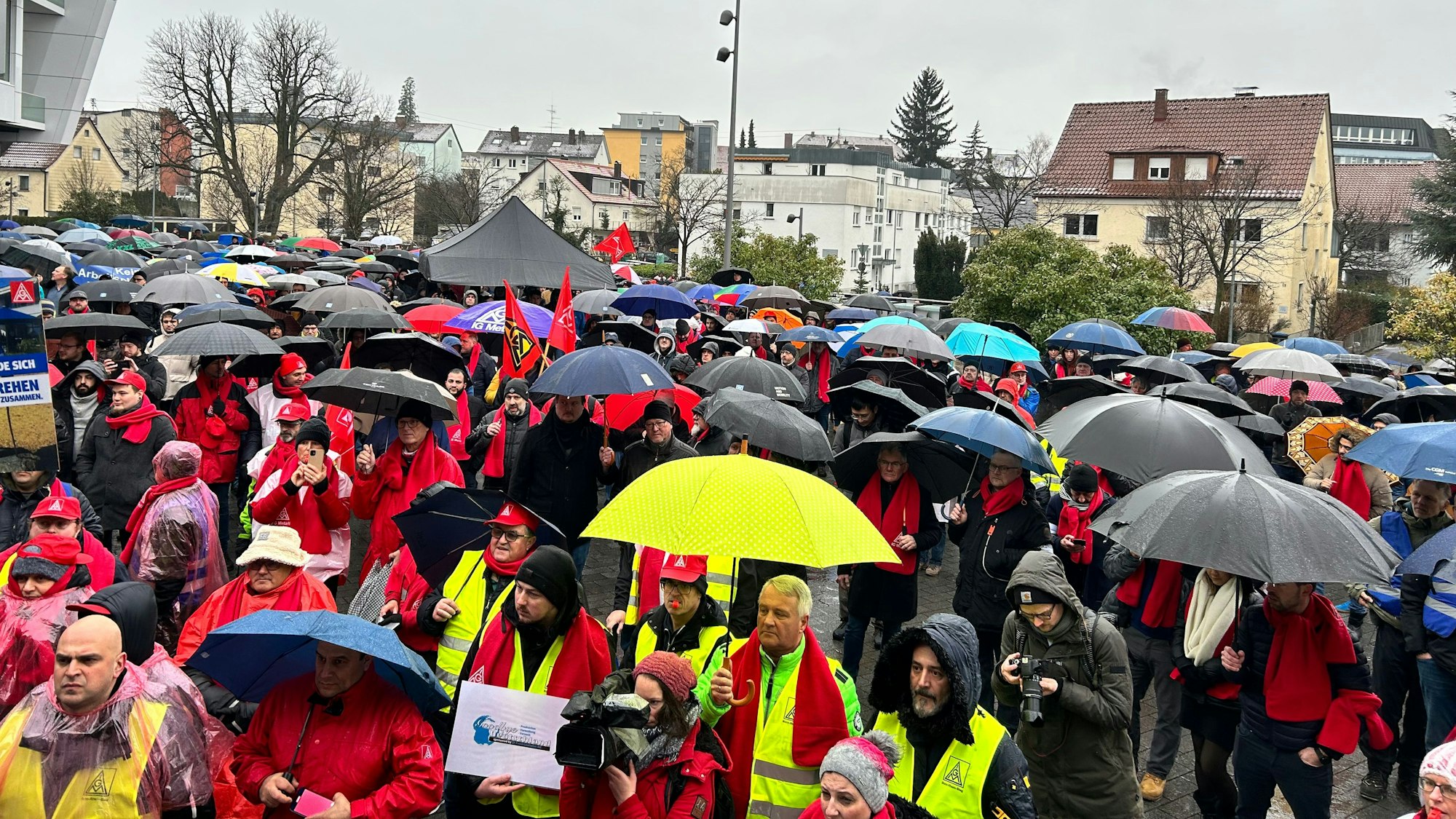 Das Bild zeigt eine große Menschenmenge mit vielen Regenschirmen bei der Protestkundgebung.