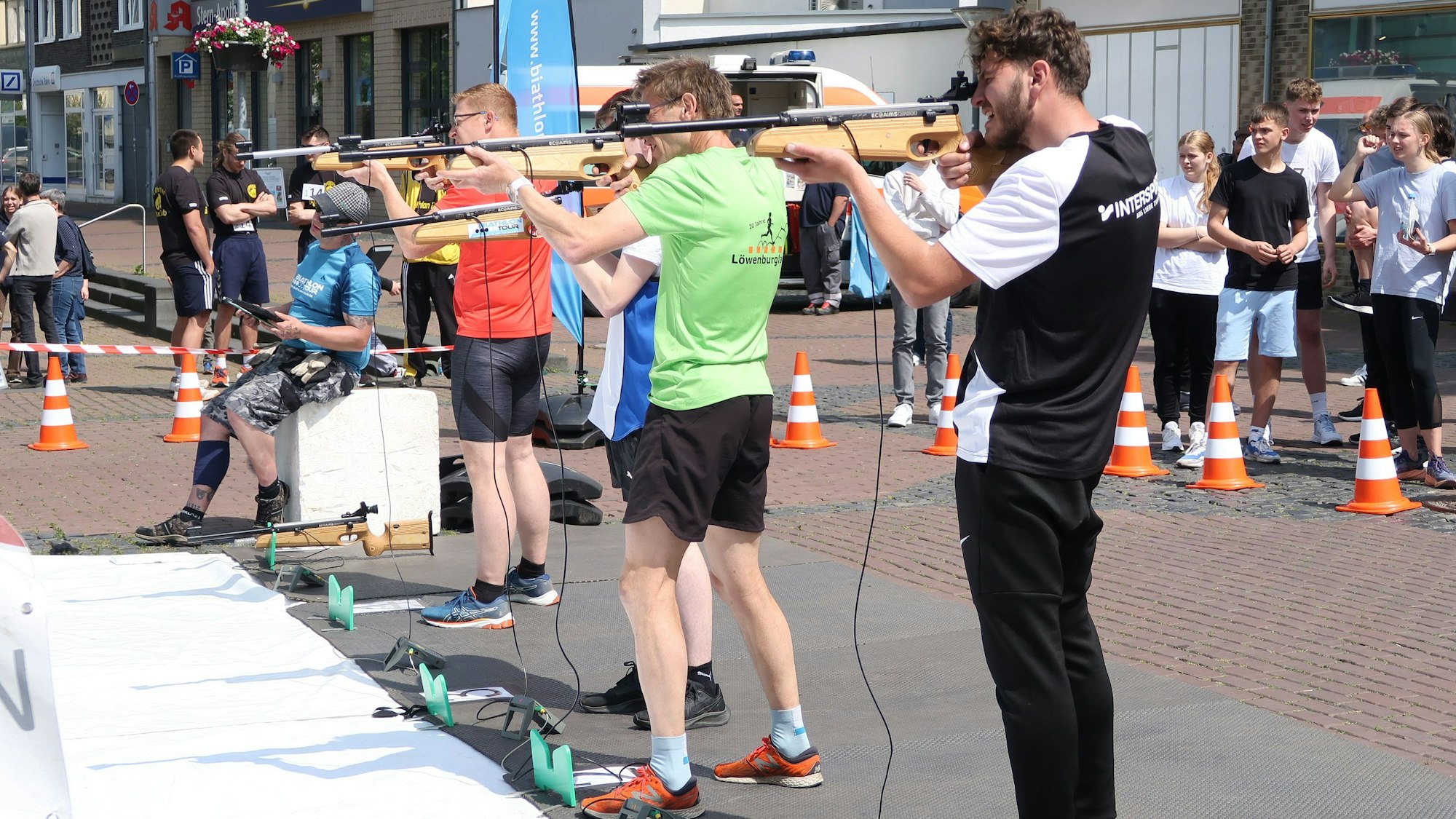 Männer stehen in einer Reihe und zielen mit einem Gewehr.