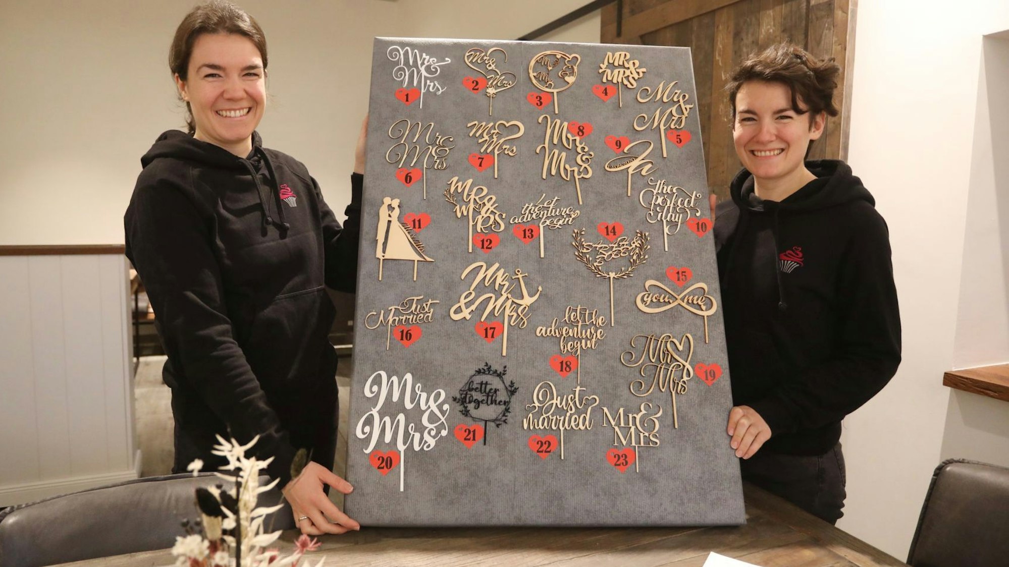 Zwei junge Frauen zeigen eine Auswahl verschiedener „Cake Topper“,