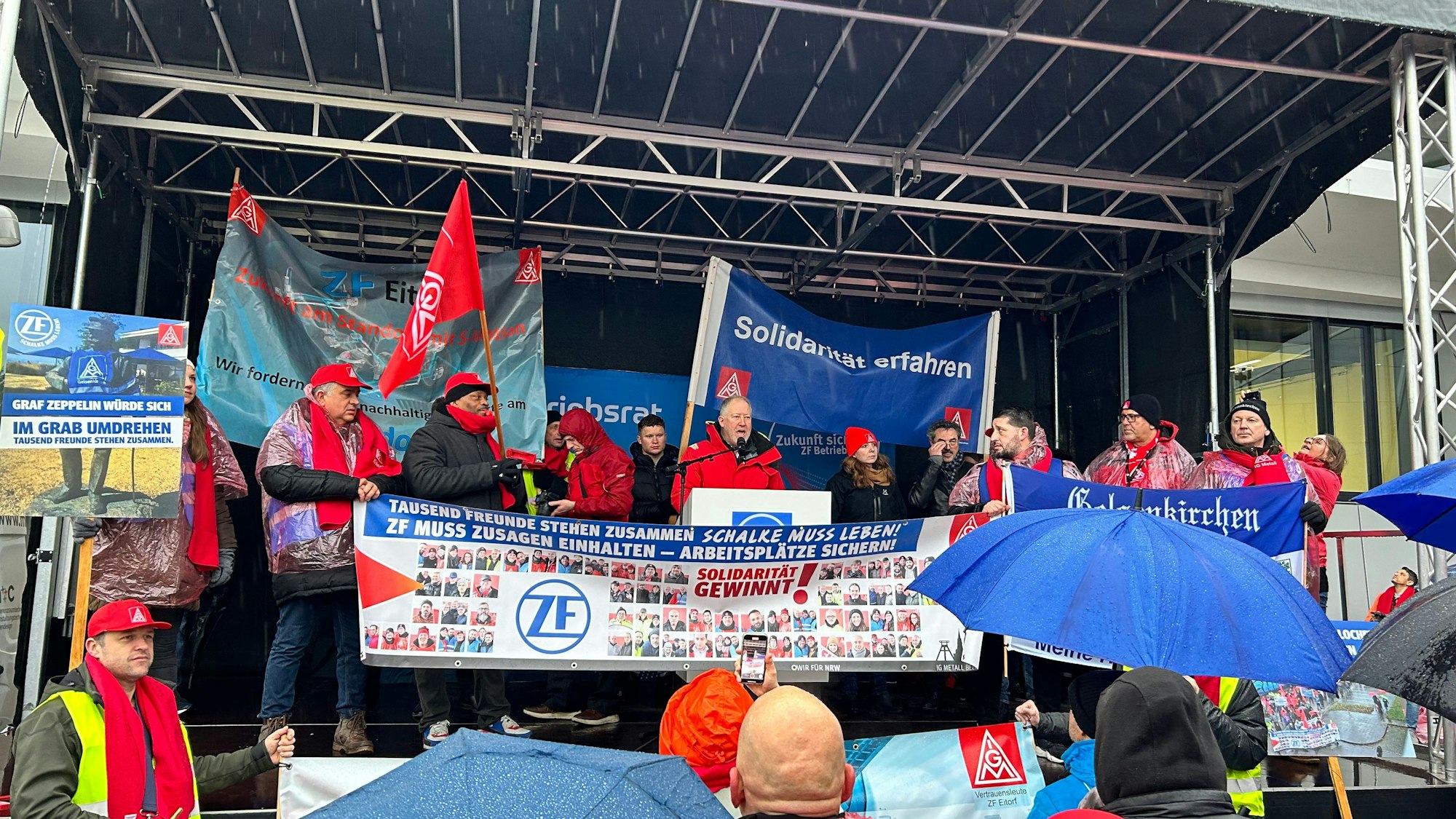 Menschen protestieren mit Bannern und Fahnen gegen eine Betriebsschließung