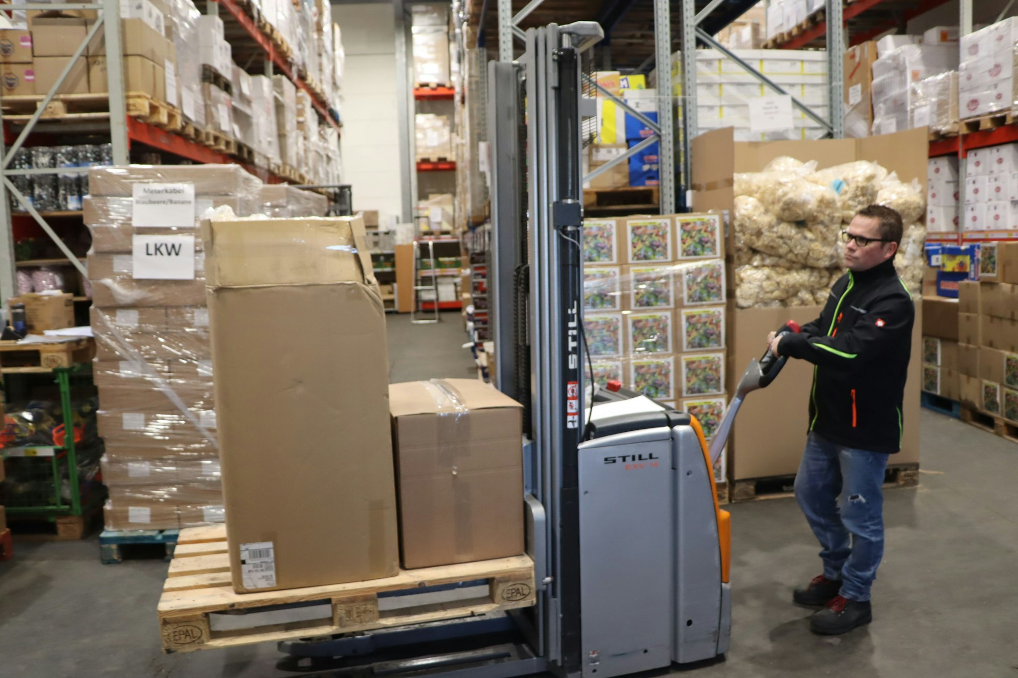 in einem Warenlager rangiert ein Mann mit einem Gabelstapler.