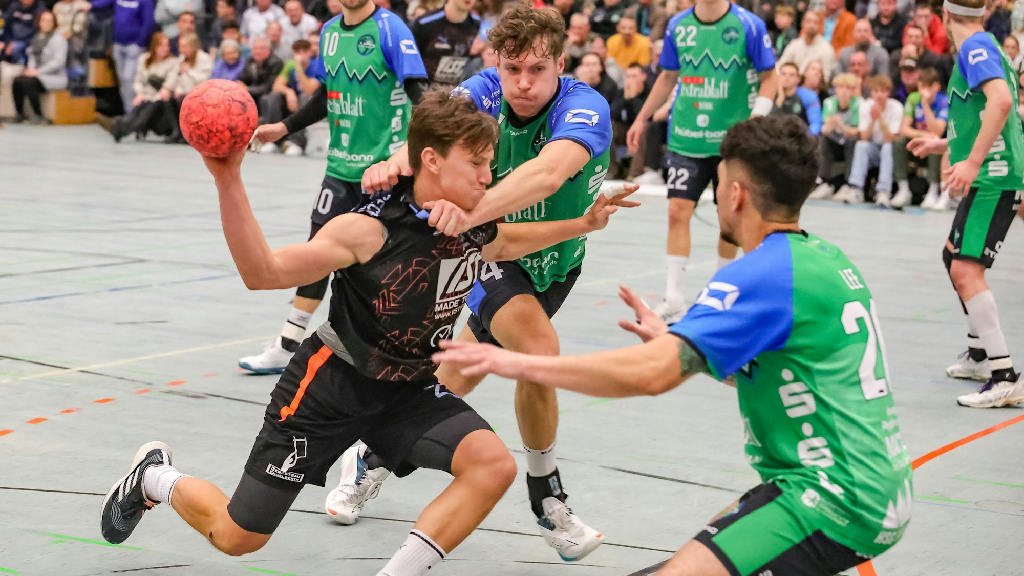 Ein Handballer wird in einer Angriffssituation von gegnerischen Spielern gedeckt.