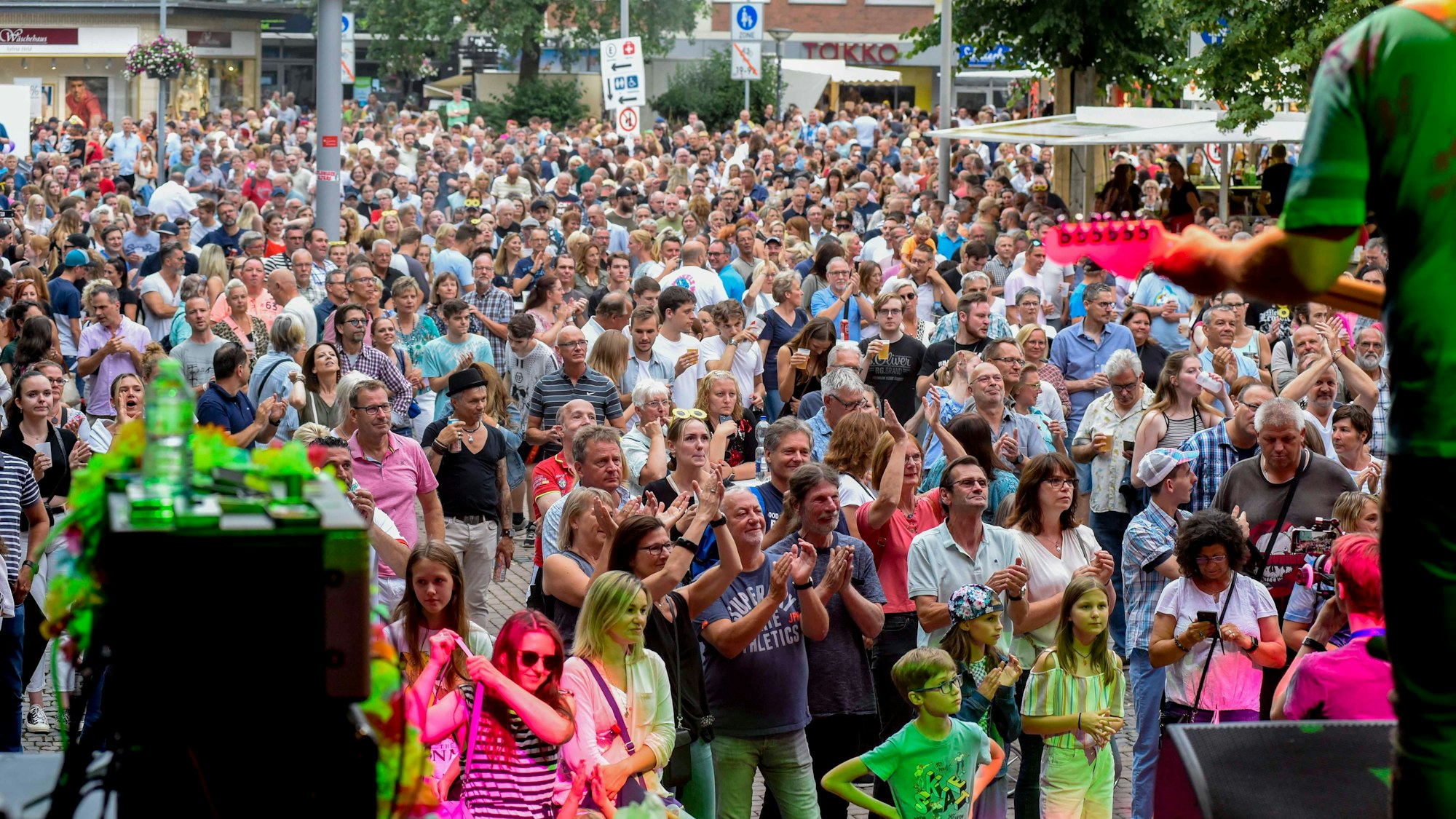 Menschen stehen vor einer Bühne und klatschen in die Hände.