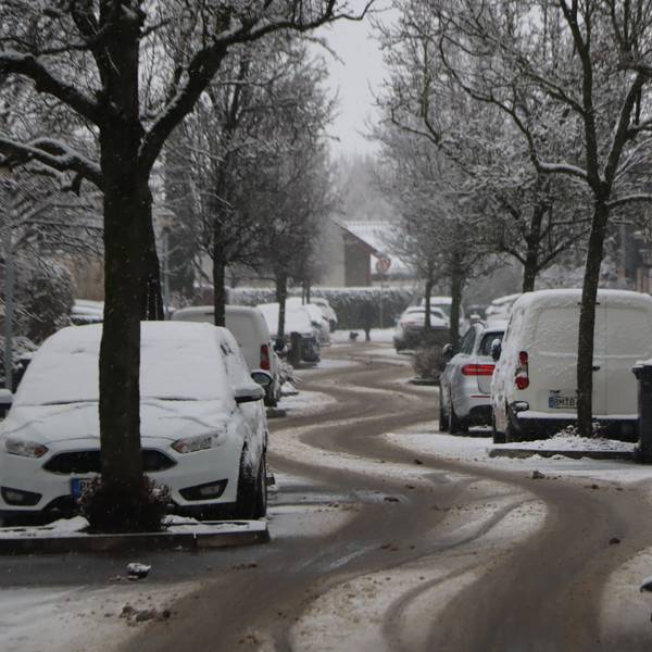 Eine verschneite Straße mit deutlichen Reifenspuren.