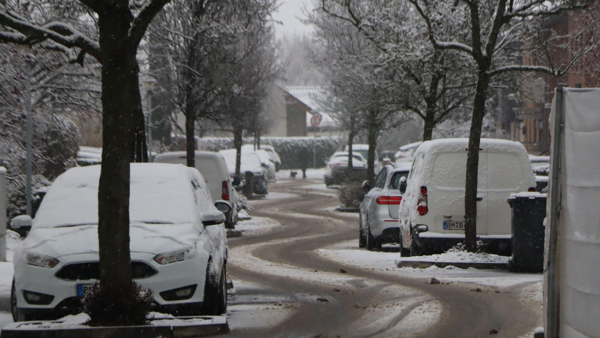 Eine verschneite Straße mit deutlichen Reifenspuren.