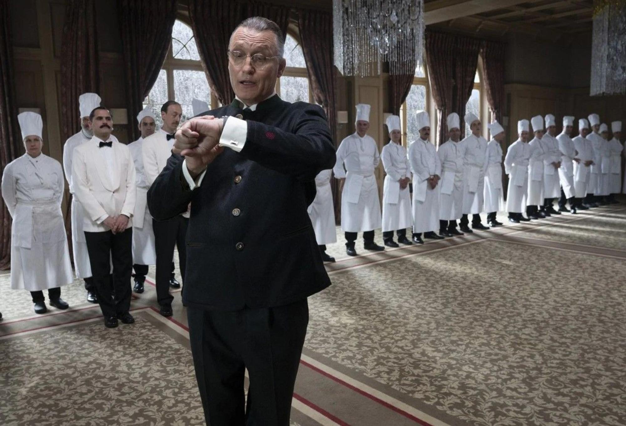 Der Schauspieler Oliver Masucci dreht eine Szene beim Film „The Palace“. Im Hintergrund stehen ganz viele Köche.
