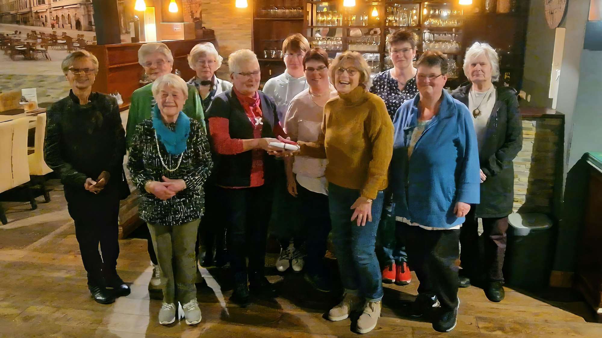 Eine Gruppe Frauen steht in einem Restaurant, im Hintergrund ist eine Theke.