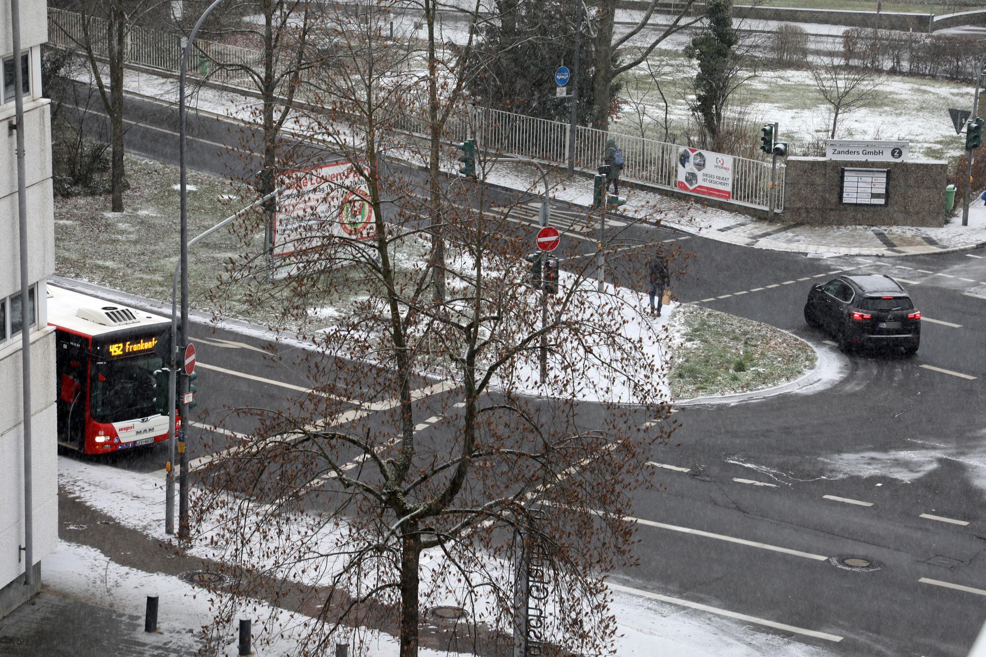 An der Straßenecke An der Gohrsmühle/Poststraße hält ein Bus, ein Auto fährt auf der noch weitgehend schneefreien Fahrbahn.