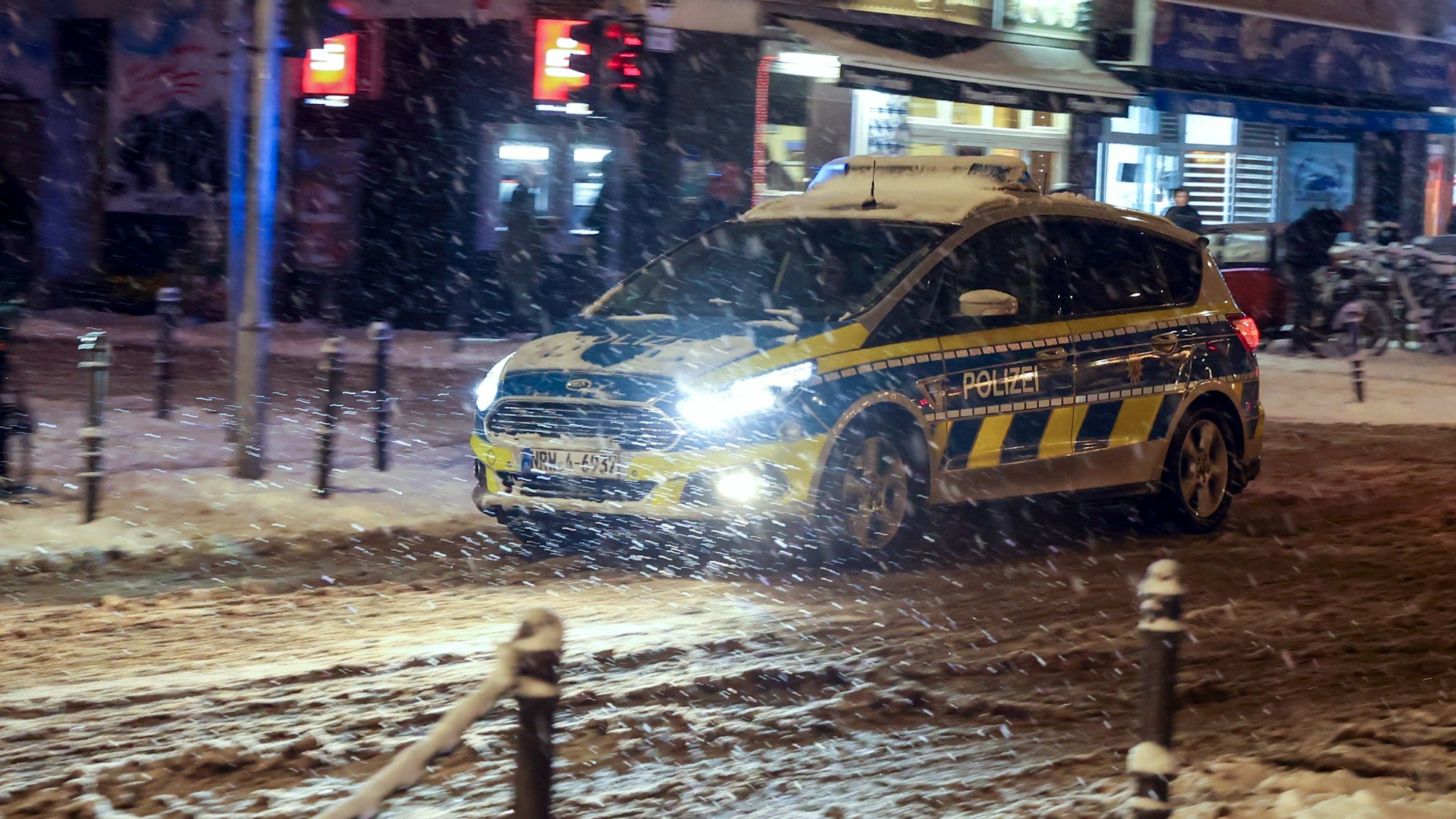 Ein Streifenwagen der Kölner Polizei ist im Schnee unterwegs.