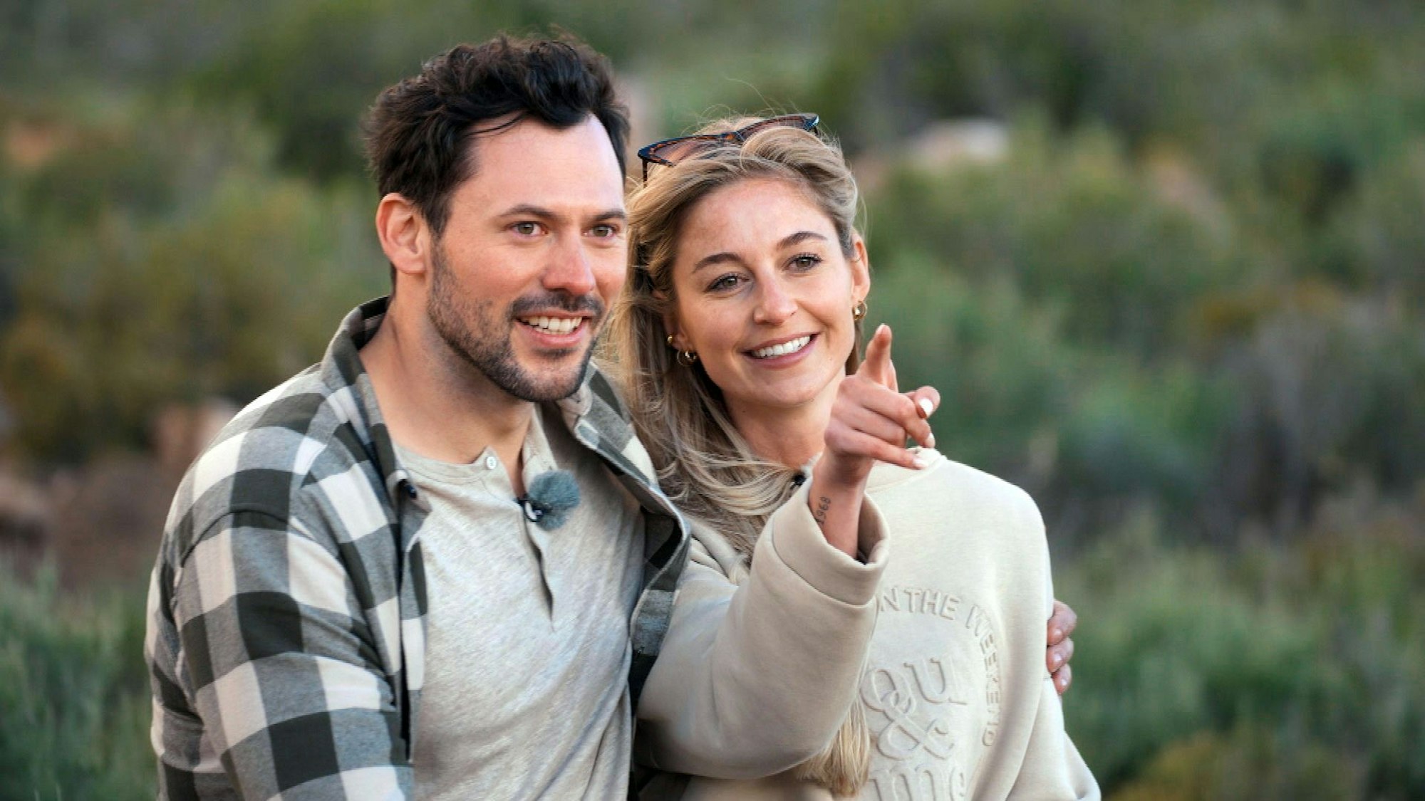 Ein Mann und eine Frau sitzen nebeneinander. Sie zeigt mit dem Zeigefinger in die Ferne.