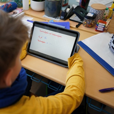 Ein Erstklässler mit einem Tablet in der Klasse.