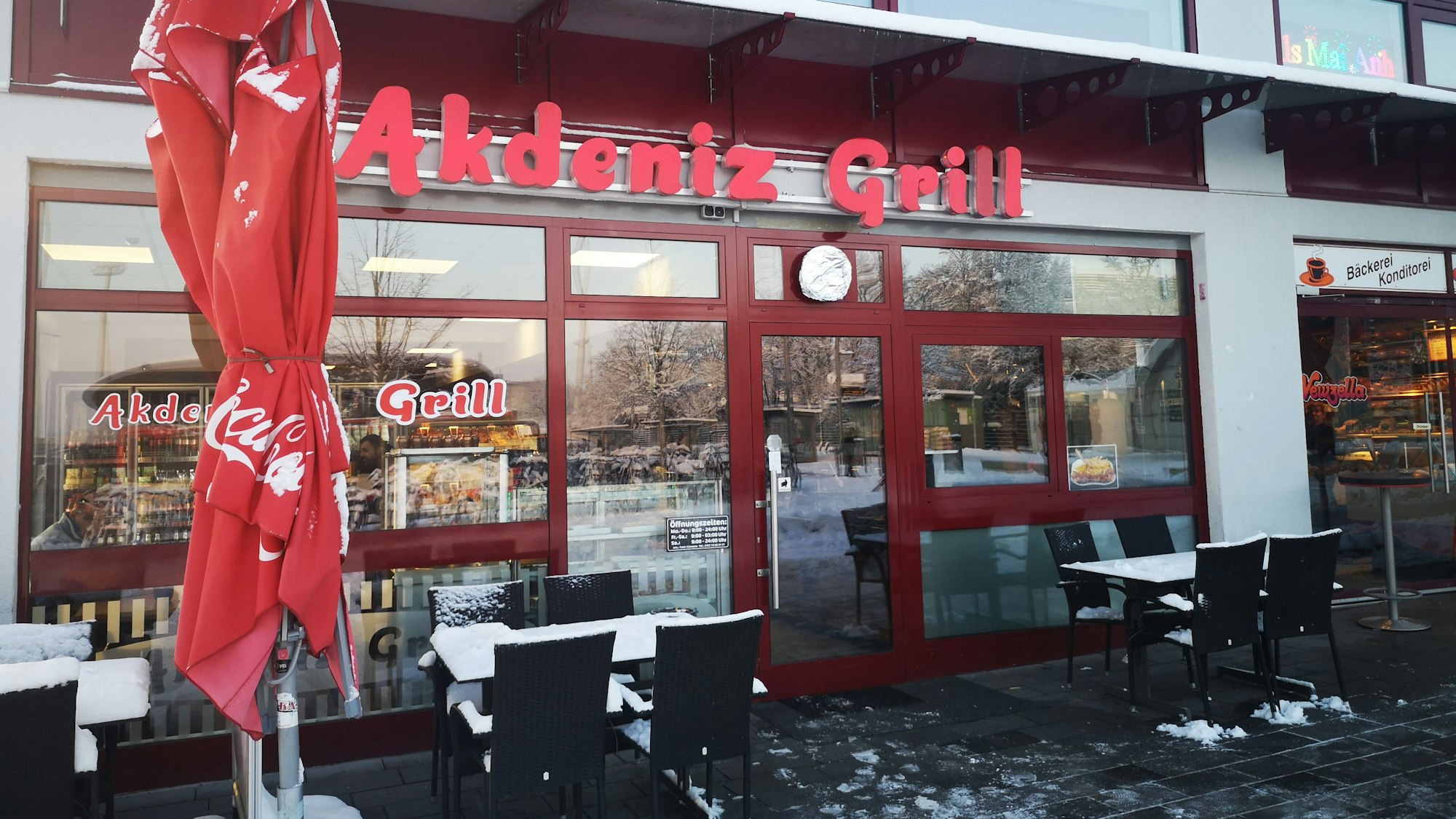 Der Eingang des Akdeniz Grill in Leverkusen Mitte von außen. Es hat geschneit. Vor dem Restaurant steht zentral links im Bild ein ausziehbarer Schirm.