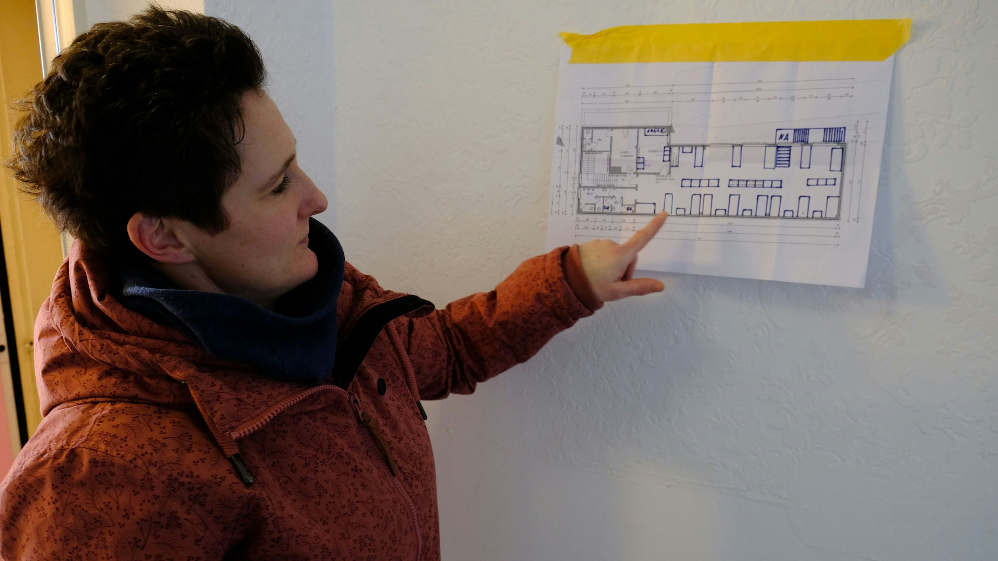 Die zuständige Fachbereichsleiterin Kati Jakob zeigt auf einen Bauplan, der an die Wand gehängt wurde.