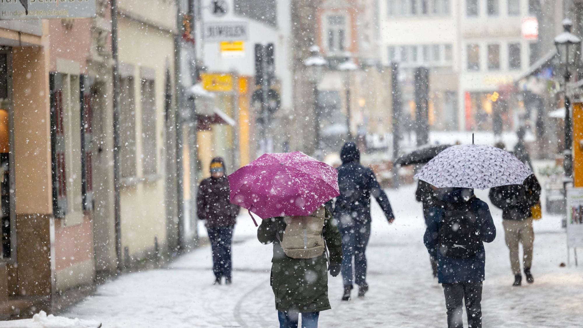 Menschen gehen bei dichtem Schneefall durch die Bonner Innenstadt.