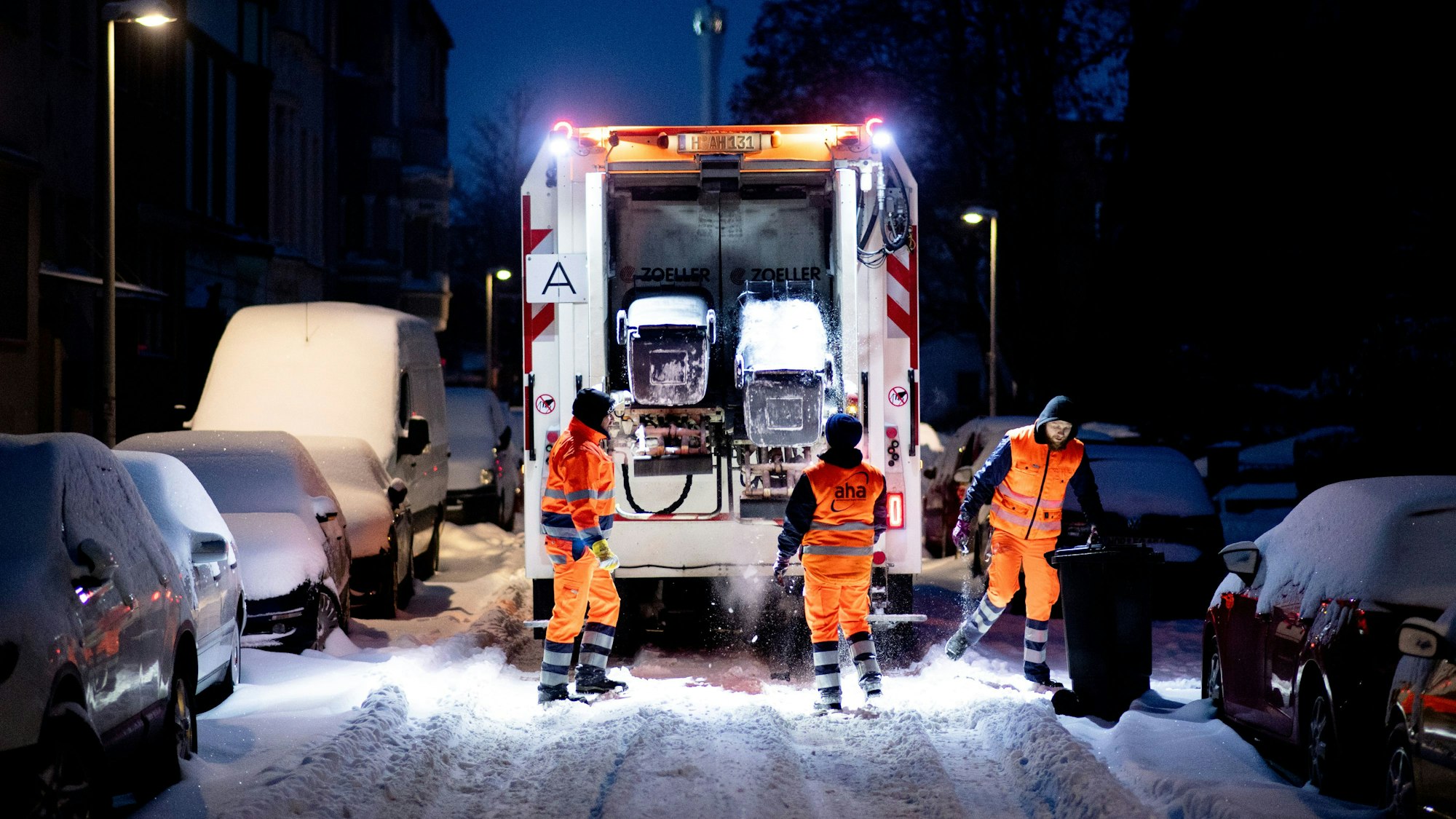 Ein Müllwagen fährt über eine zugeschneite Straße.