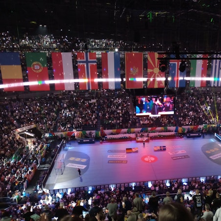 Eine Eventhalle voller Publikum wird bunt ausgeleuchtet.