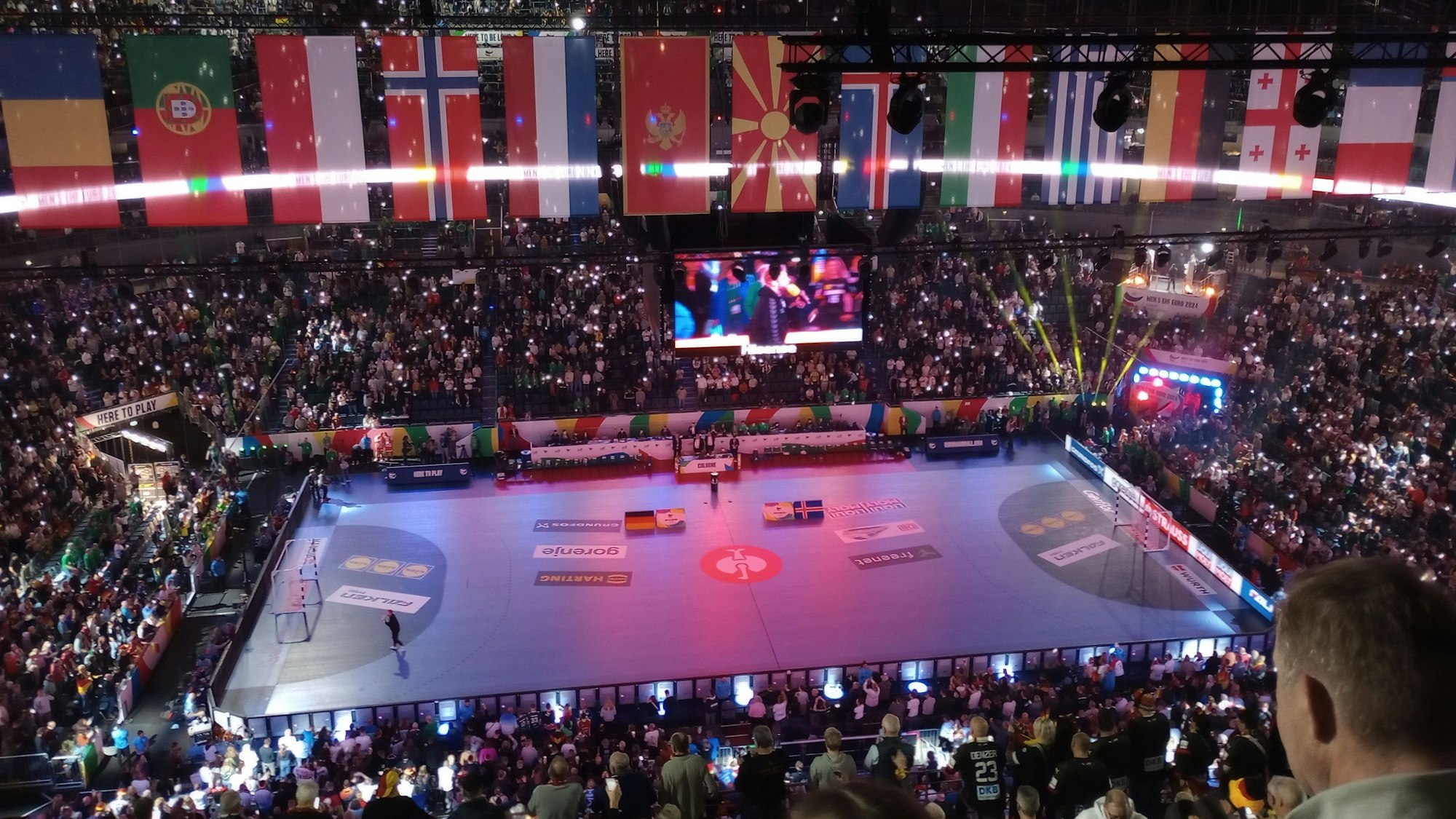 Eine Eventhalle voller Publikum wird bunt ausgeleuchtet.