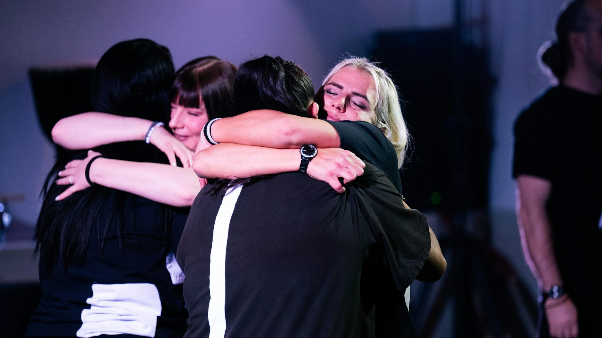 Schauspielerinnen und Schauspieler der JVA Ossendorf umarmen sich auf der Bühne.