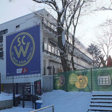 Blick auf ein dreistöckiges Gebäude mit dem Banner des SC West.
