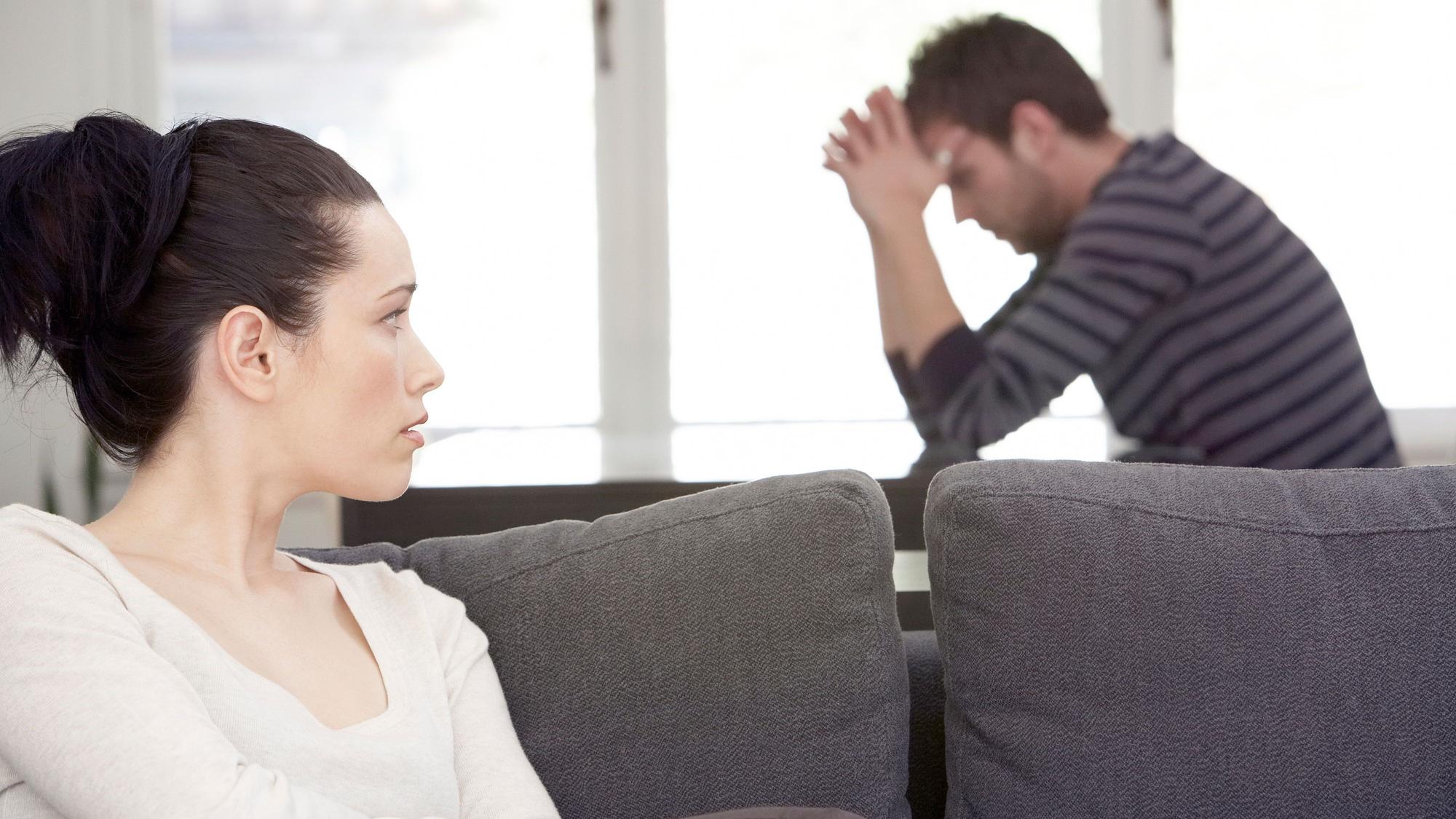 Frau und Mann sitzen zerstritten im Wohnzimmer
