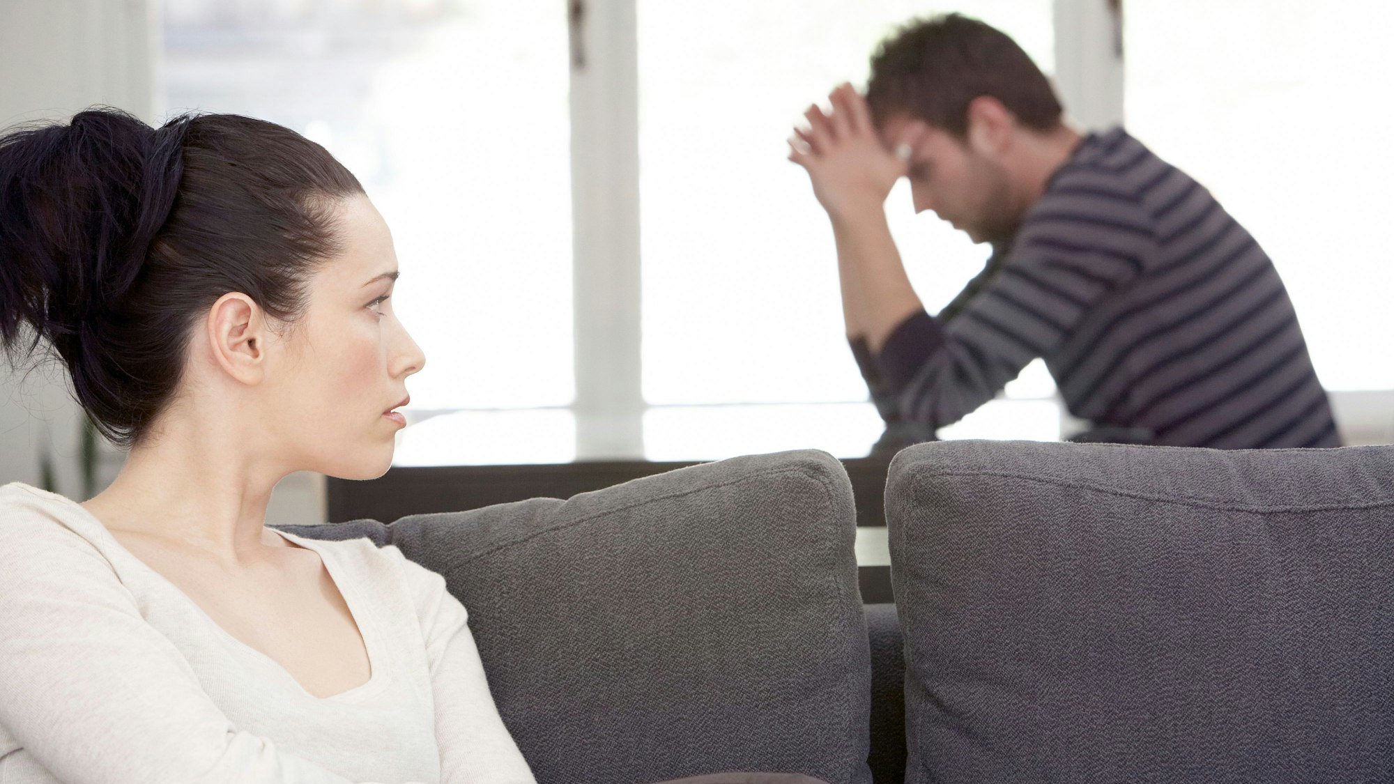 Frau und Mann sitzen zerstritten im Wohnzimmer