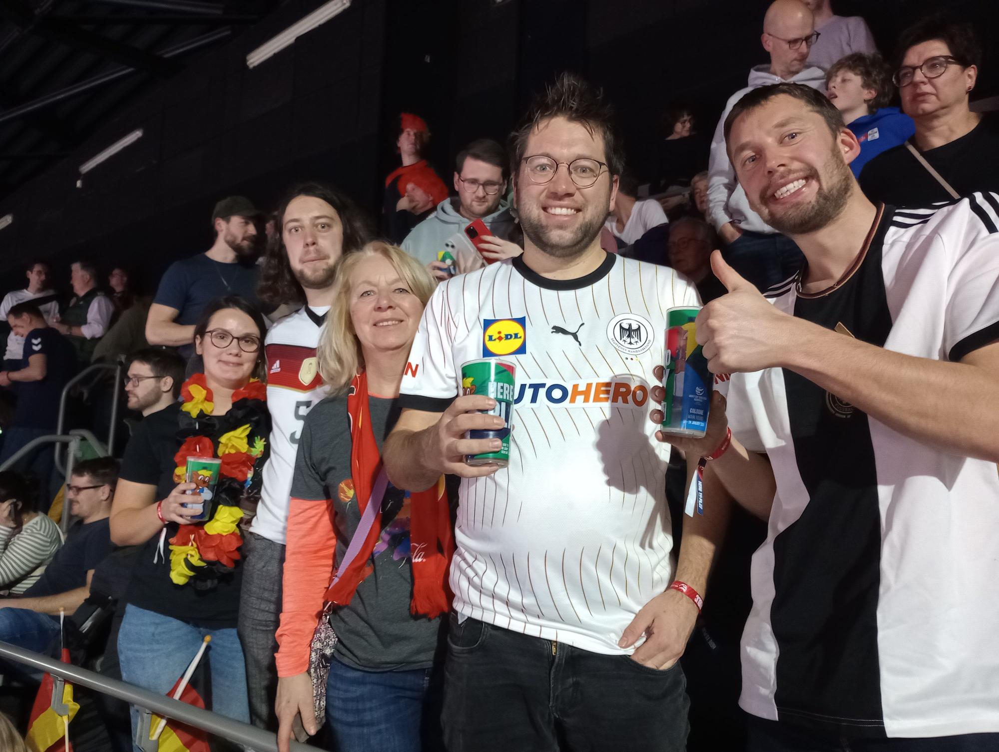 Handball-Fans stehen auf einer Tribüne.