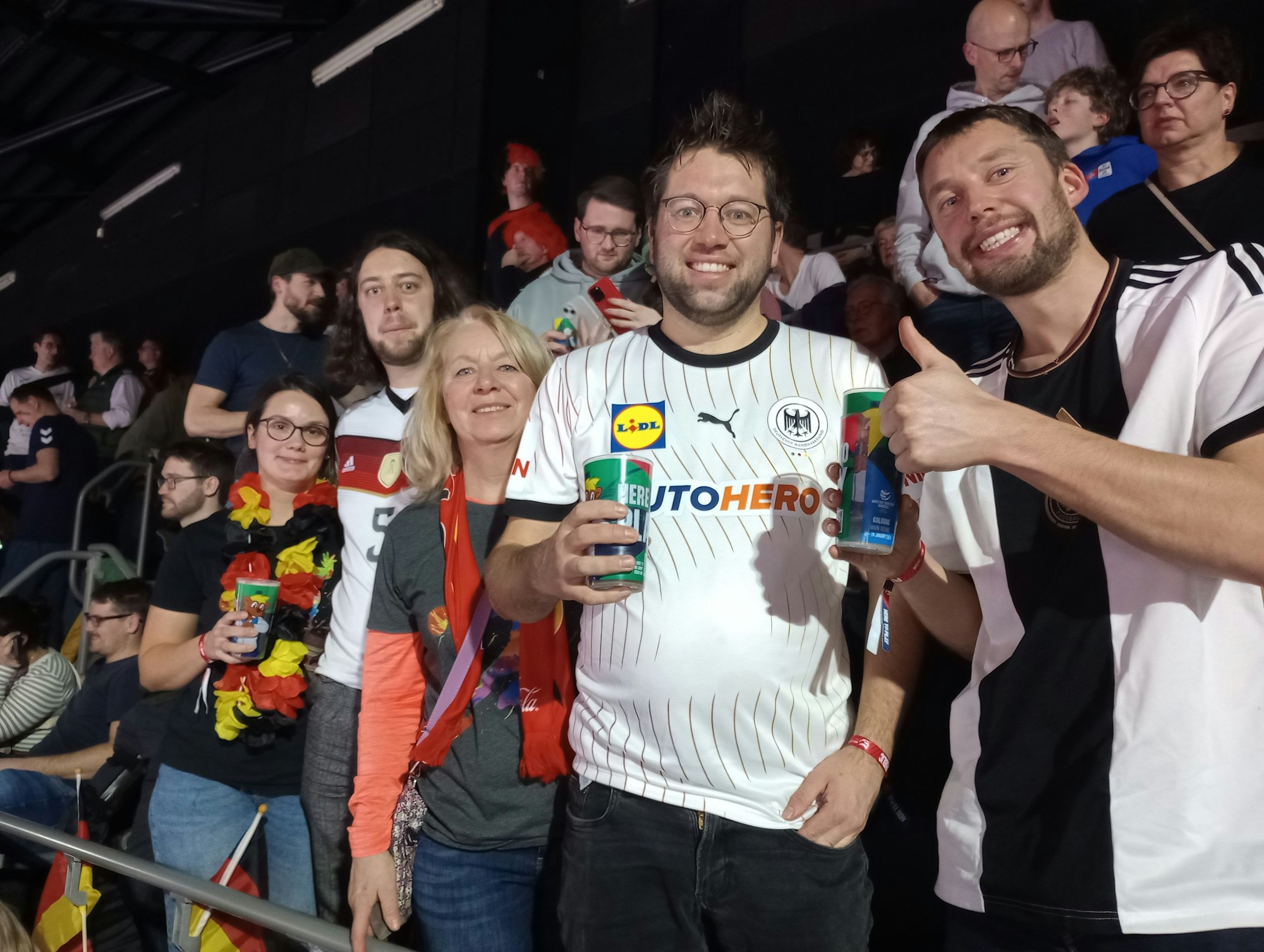 Handball-Fans stehen auf einer Tribüne.