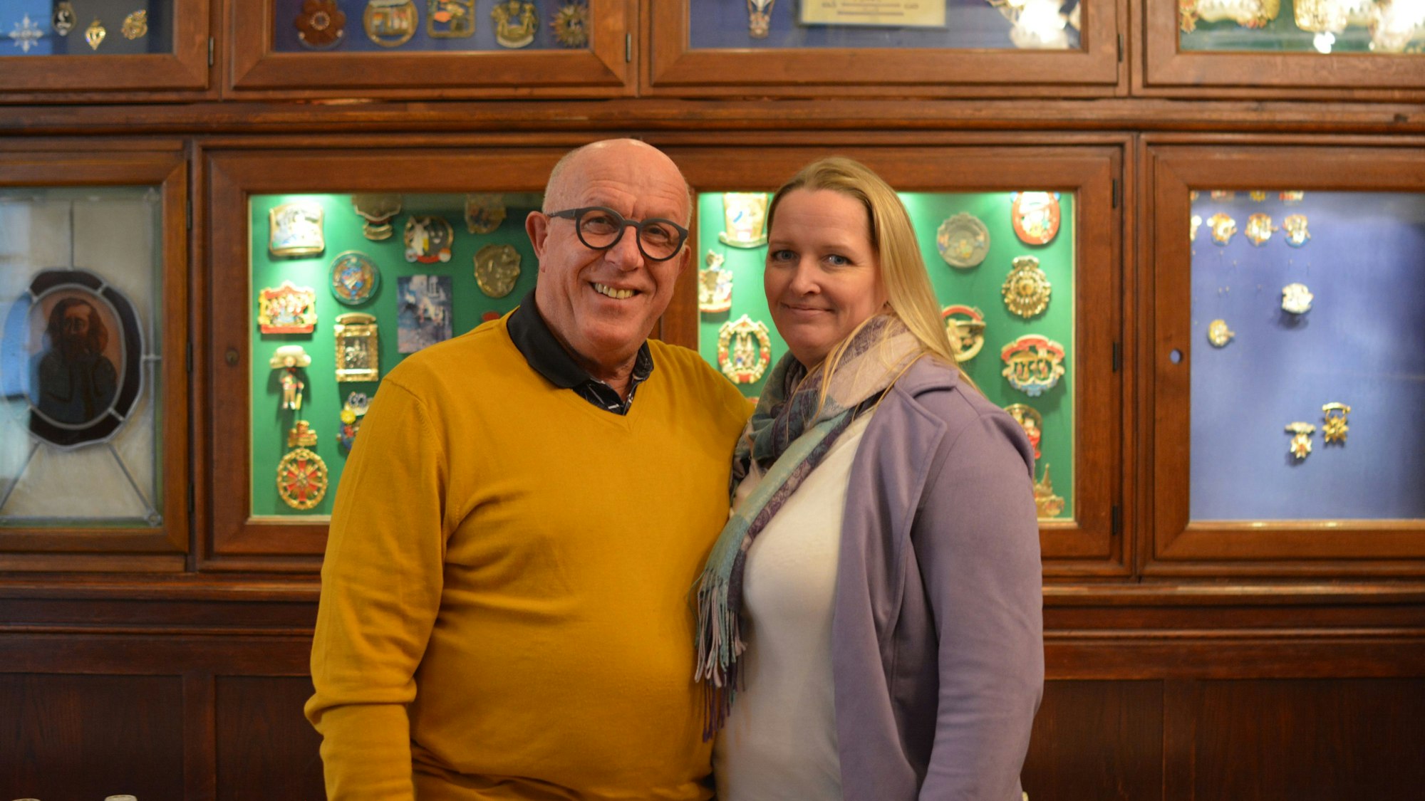 Ein Mann und eine Frau stehen vor einer Wand mit Karnevalsorden.