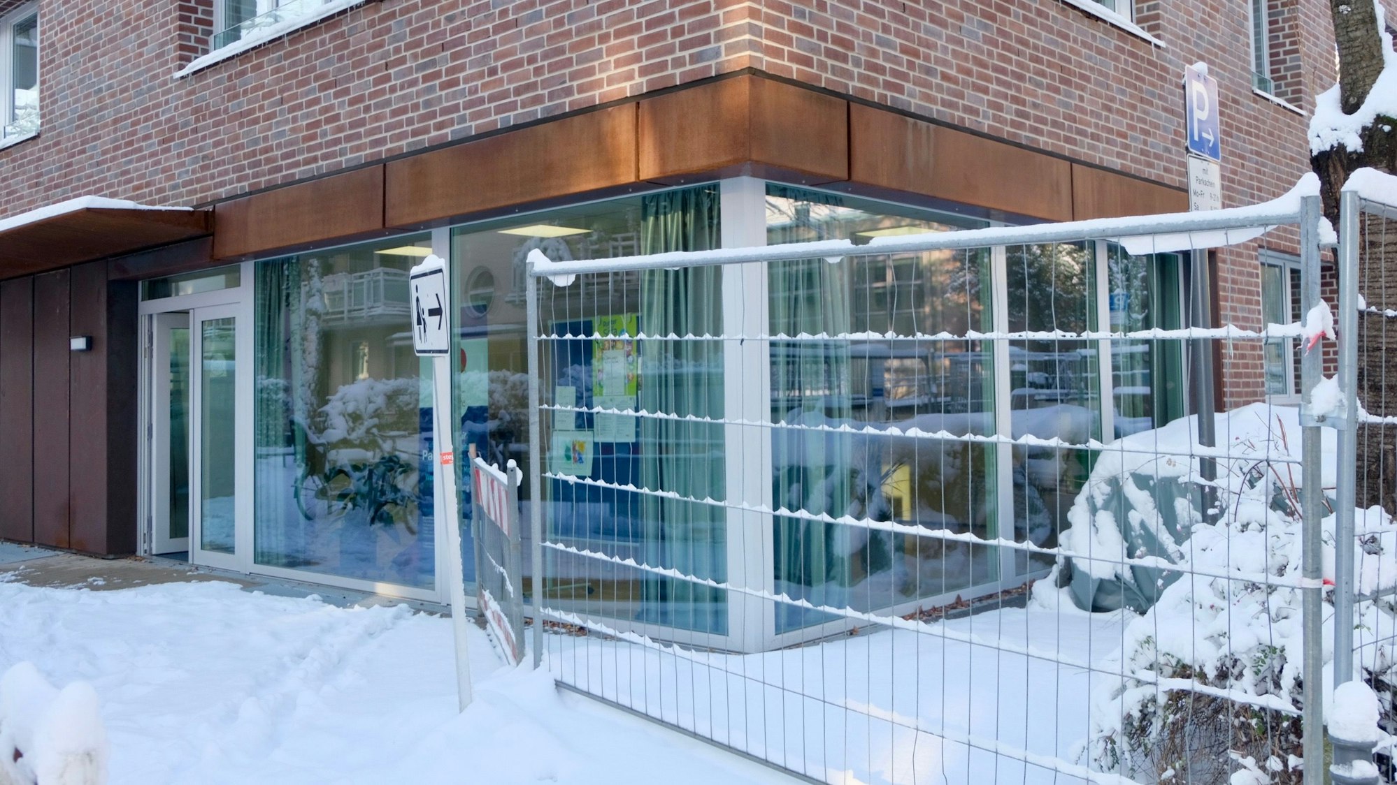 Ein neu gebautes Haus mit Glasfenstern im Erdgeschoss und einem Bauzaun sind zu sehen.